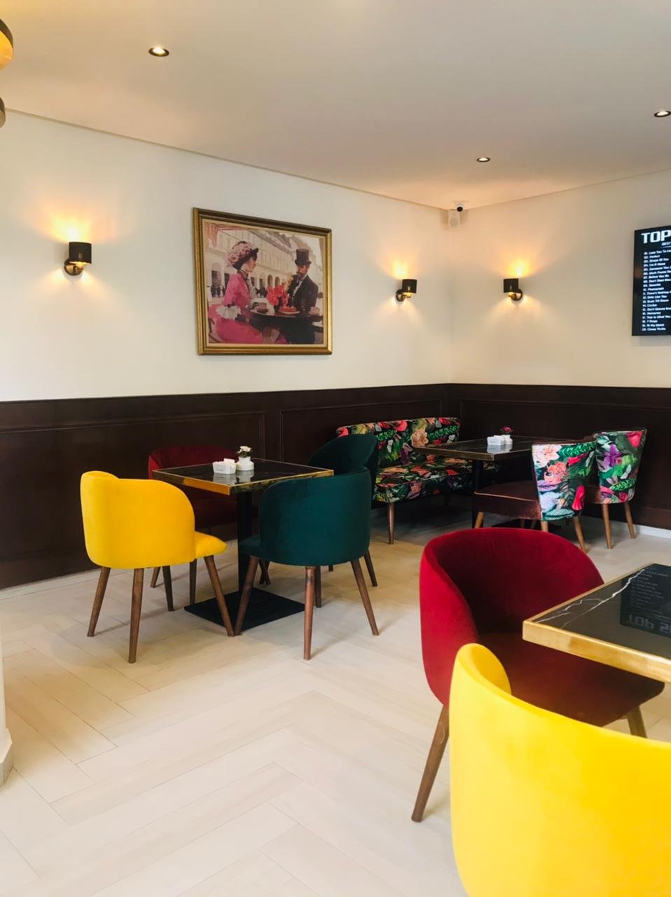 Banquettes et fauteuils colorés d'un café avec appliques murales