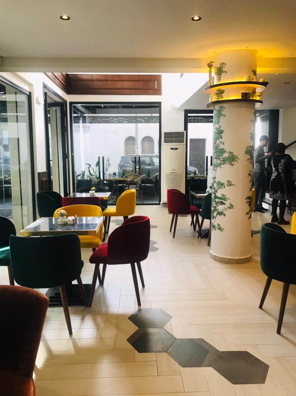 Salle de café avec fauteuils colorés et colonne peinte en trompe-l'œil