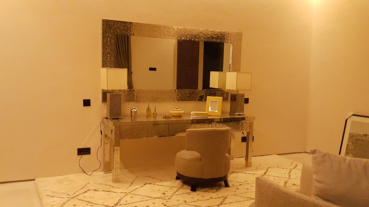 Coiffeuse avec grand miroir doré et pouf dans une suite