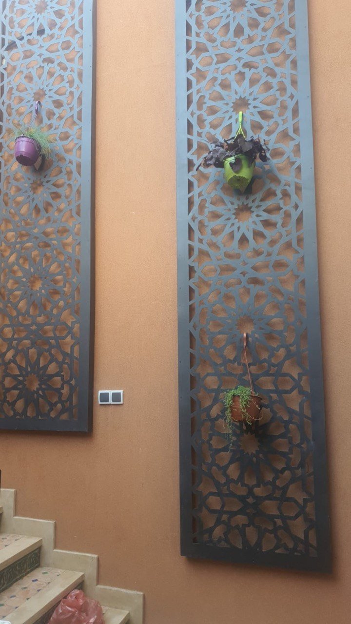 Panneaux moucharabieh en métal découpé sur mur ocre de patio