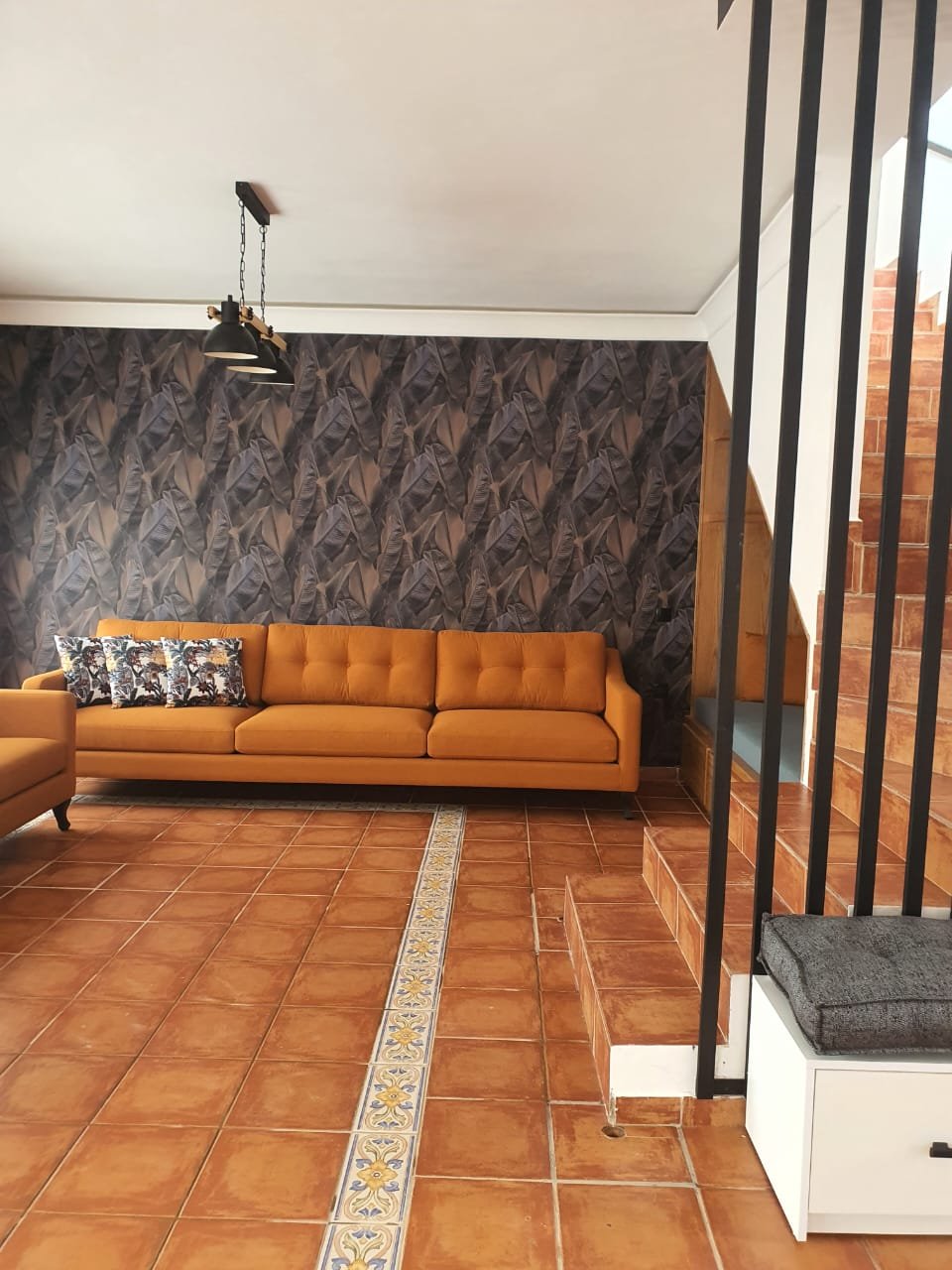 Séjour au sol en terre cuite avec canapé orange et papier peint à motifs